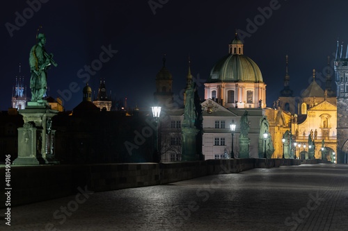 lights on the Charles Bridge on the Vltava river at night and in the background the bridge tower