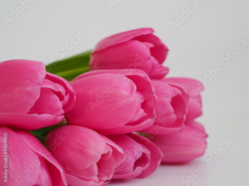 Bouquet of tulips wrapped in craft paper on pink background with space for text. Greeting card. Concept woman's or mother's day. Spring flowers background. Close-up