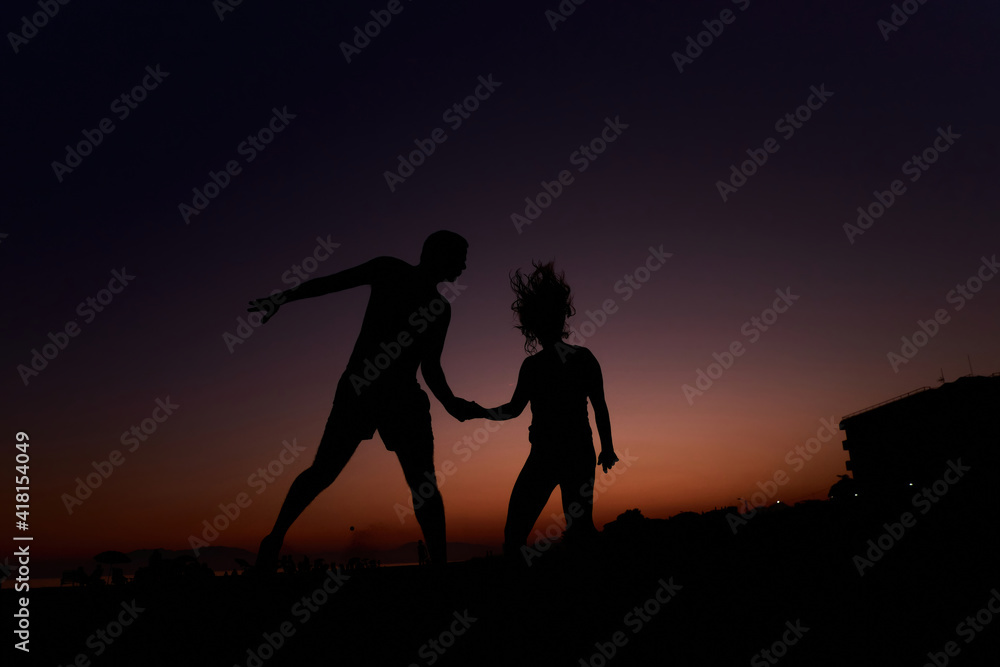 Silhouette of a couple jumping on the beach at sunset