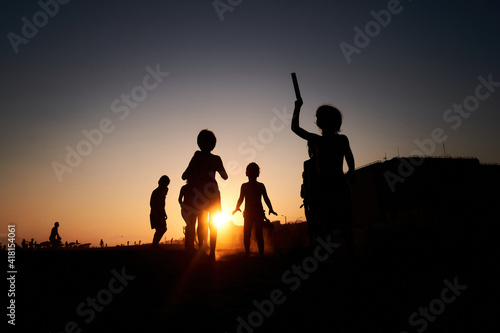 Happy children's silhouettes on the summer beach running and jumping