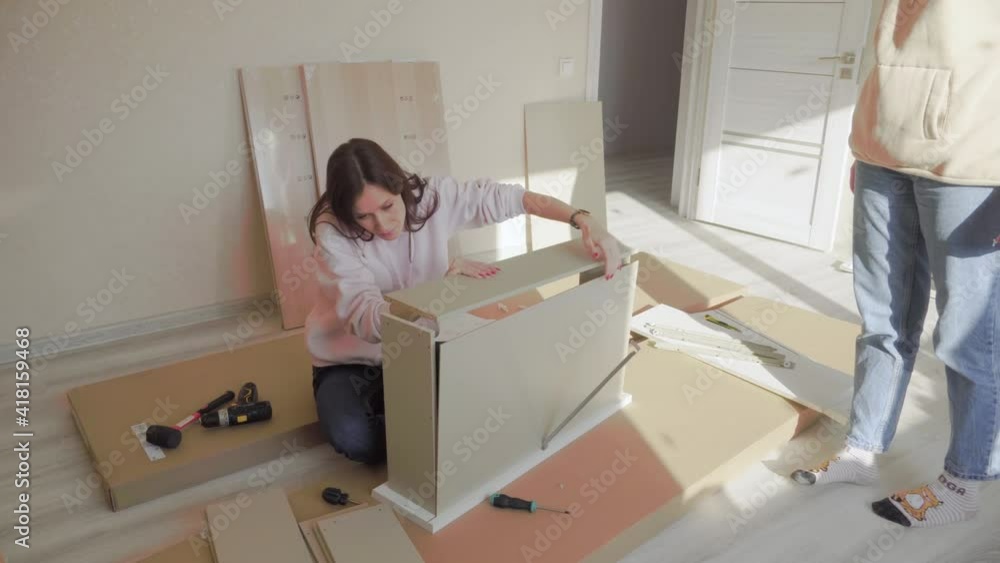 Women self assembling furniture together. Moving in new house Women self assembling furniture together. Moving in new house