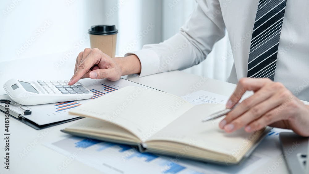 Business man hold pen and press calculator to check investment data Business man hold pen and press calculator to check investment data