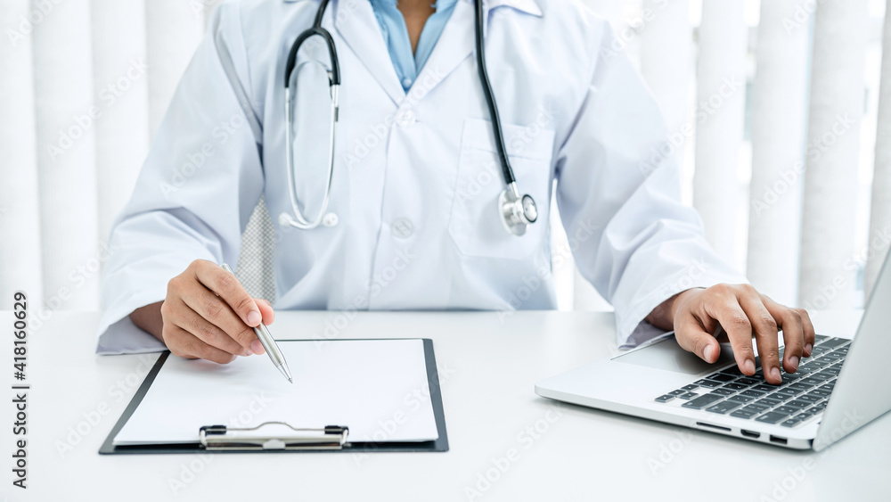 Doctor hold pen to record patient data on clipboard and computer Doctor hold pen to record patient data on clipboard and computer