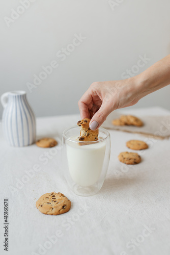Female hand dipping cookies in milk. Oatmeal cookies and milk.