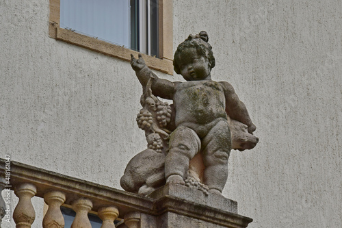 Statue of a girl with a dog and grapes on the balcony of an old building