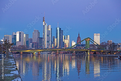 Picture of Frankfurt skyline during sunrise with reflections of skyscraper facades in Main river under cloudless and colorful sky