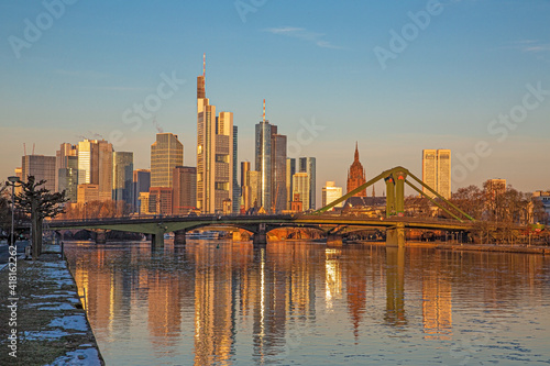 Picture of Frankfurt skyline during sunrise with reflections of skyscraper facades in Main river under cloudless and colorful sky © Aquarius