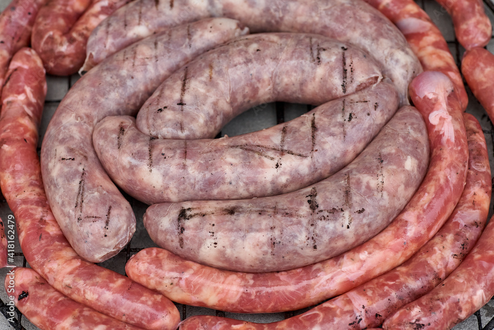 Fototapeta premium Sausages on the barbecue grill, raw sausages