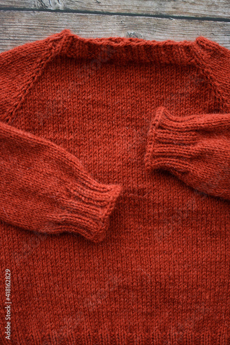Red woolen handmade baby sweater on gray background