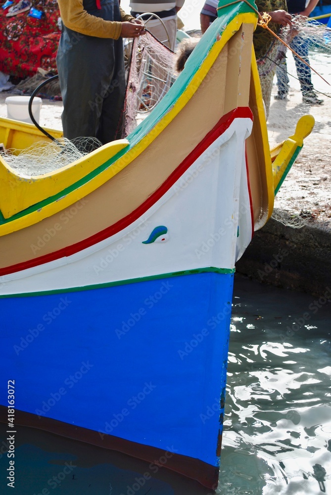 Obraz premium Maltese boats – the Luzzu and the Dgħajsa - float in the harbor of Marsaxlokk, Malta. the fishing boats are decorated with the eye of Osiris to keep the fishers safe at sea.
