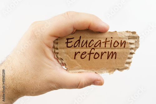 A man holds a cardboard in his hand on which it is written - Education reform photo