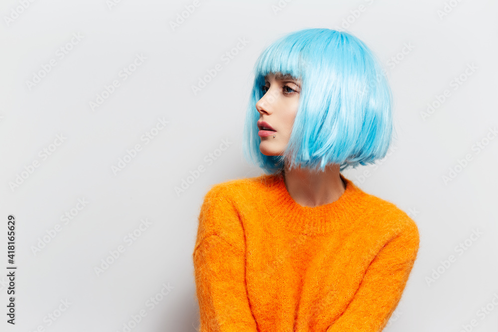 Studio side portrait of young girl with blue hair in orange sweater against white background. Studio side portrait of young girl with blue hair in orange sweater against white background.