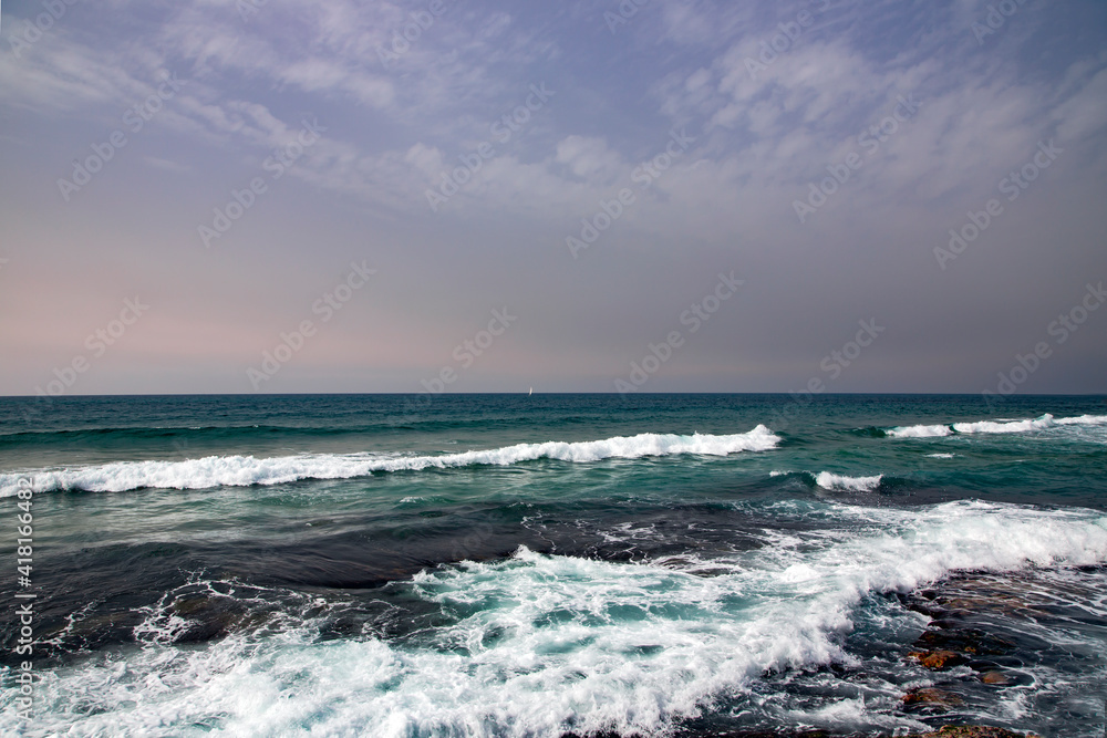 Beautiful clear sea water of Mediterranean sea on sunset. Sea waves break on the shore after a storm.