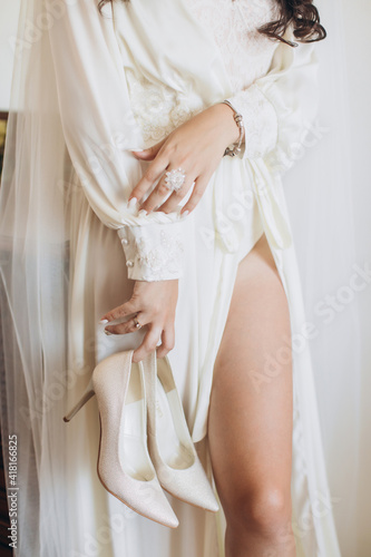 Happy beautiful bride. Beautiful bride shows makeup and hairstyle. Bride in a white dress plays with her veil. Fashion, beauty, style. Morning of the bride.
