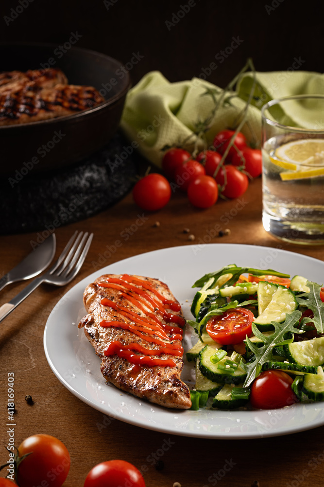 Fried chicken steak with fresh vegetable salad on a plate on wooden background. Close up. Low key