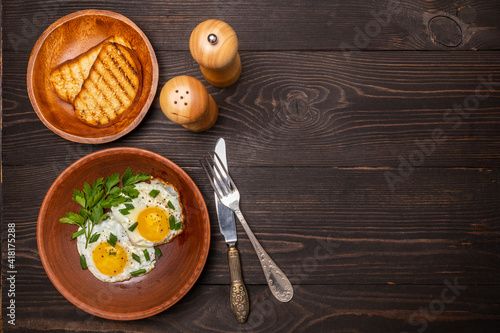 fried eggs with herbs on a clay plate top view