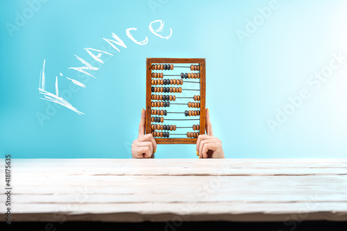 Girl holding old wooden scratched vintage decimal abacus on a blue blank background. Space for text. Mock up