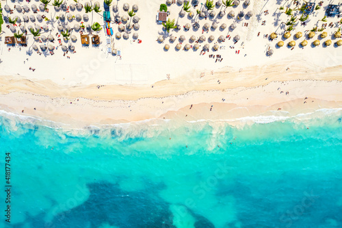 Beach vacation and travel background. Aerial drone view of beautiful atlantic tropical beach with straw umbrellas and palms. Bavaro beach, Punta Cana, Dominican Republic.