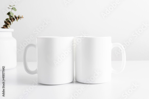 Two mugs mockup with workspace accessories, dried flowers in vase on white table. Front view. Place for text, copy space, mockup