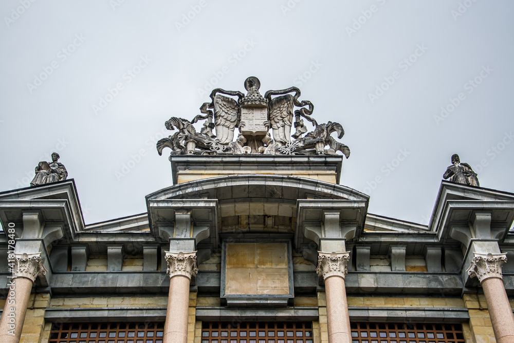 Antiguo escudo de España sobre columnas en la fachada principal interior de la antigua Universidad Laboral de Gijón, España
