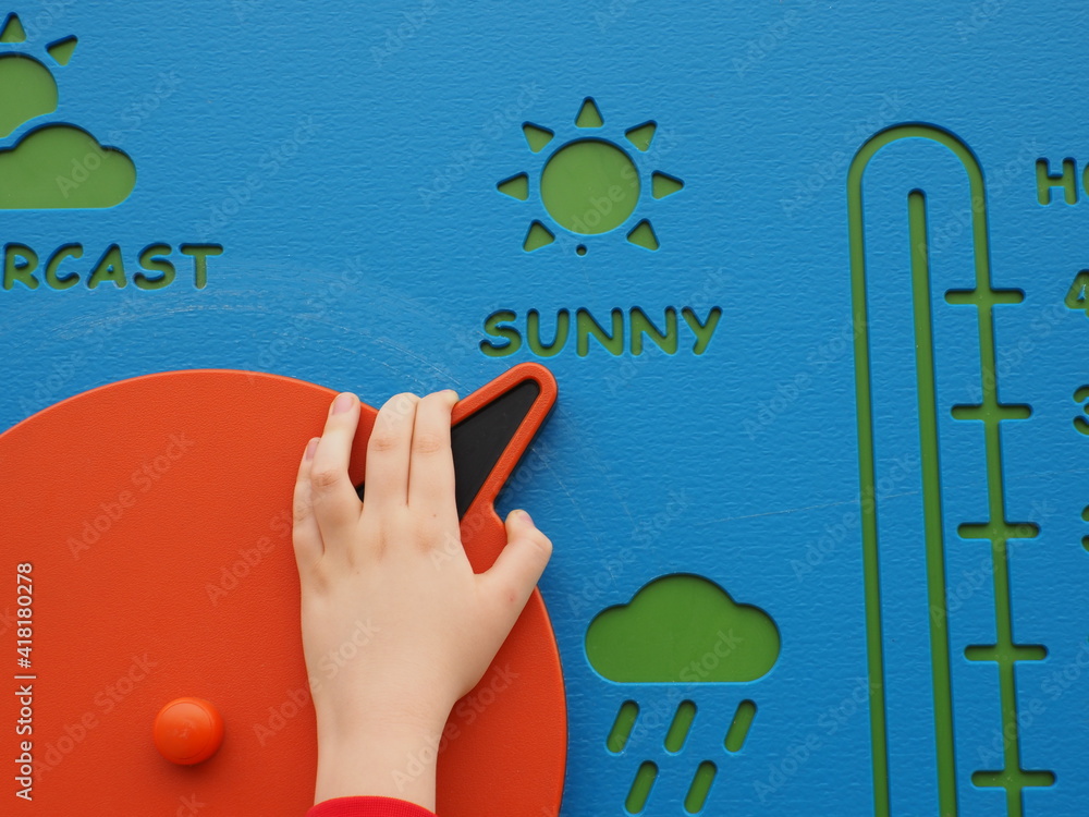 Φωτογραφία Kid's hand moving the arrow of a weather wheel