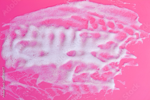 Foam bubbles and brick of soap on pink background. Cleaning service
