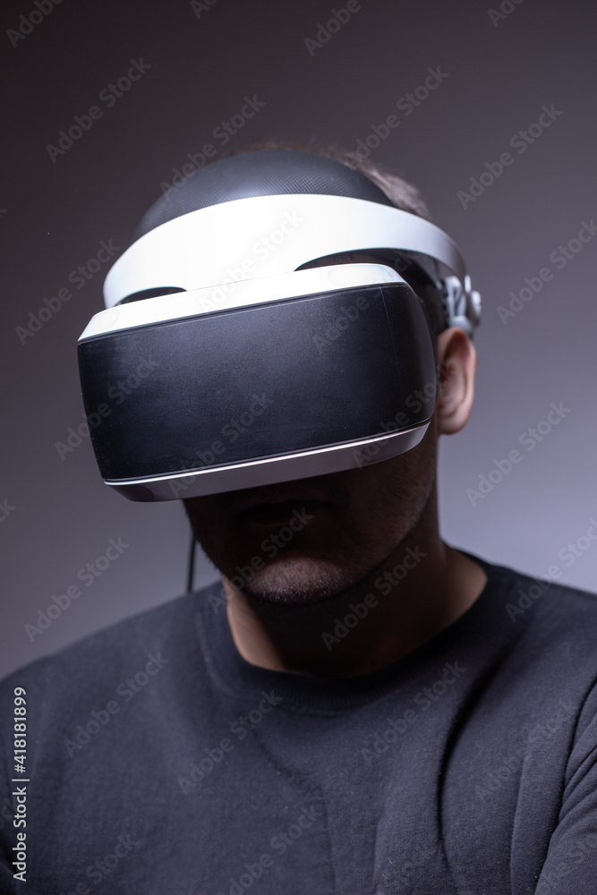Man in his thirties wearing virtual reality glasses on a dark background. Concept of artificial intelligence, hacking, fraud. Copy space Man in his thirties wearing virtual reality glasses on a dark background. Concept of artificial intelligence, hacking, fraud. Copy space