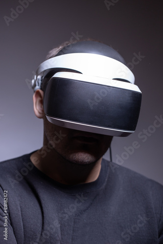 Close-up of a man in his thirties wearing virtual reality glasses on a dark background. Concept of artificial intelligence, hacking, fraud. Copy space