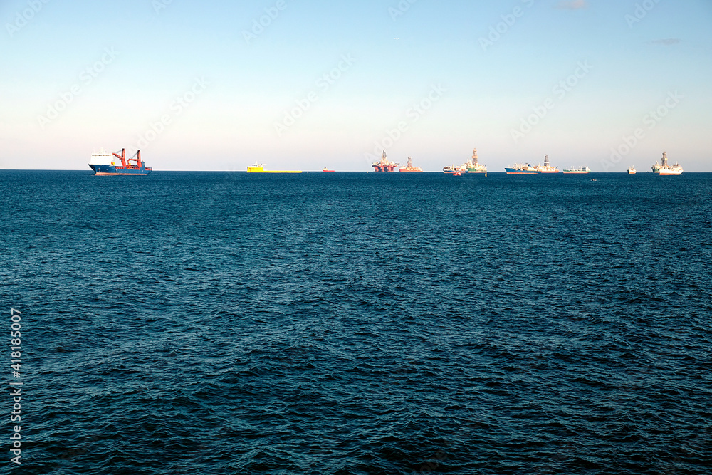 Oil rigs, tugs and various service ships anchored in the outer harbour waiting for refueling and repair.