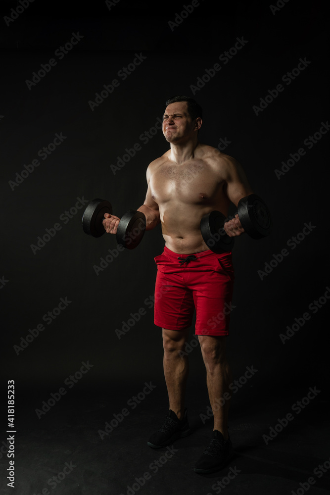 Fitness man presses dumbbells in red panties business man, attractive isolated bodybuilder. Handsome studio, fashionable elegance background black bodybuilder