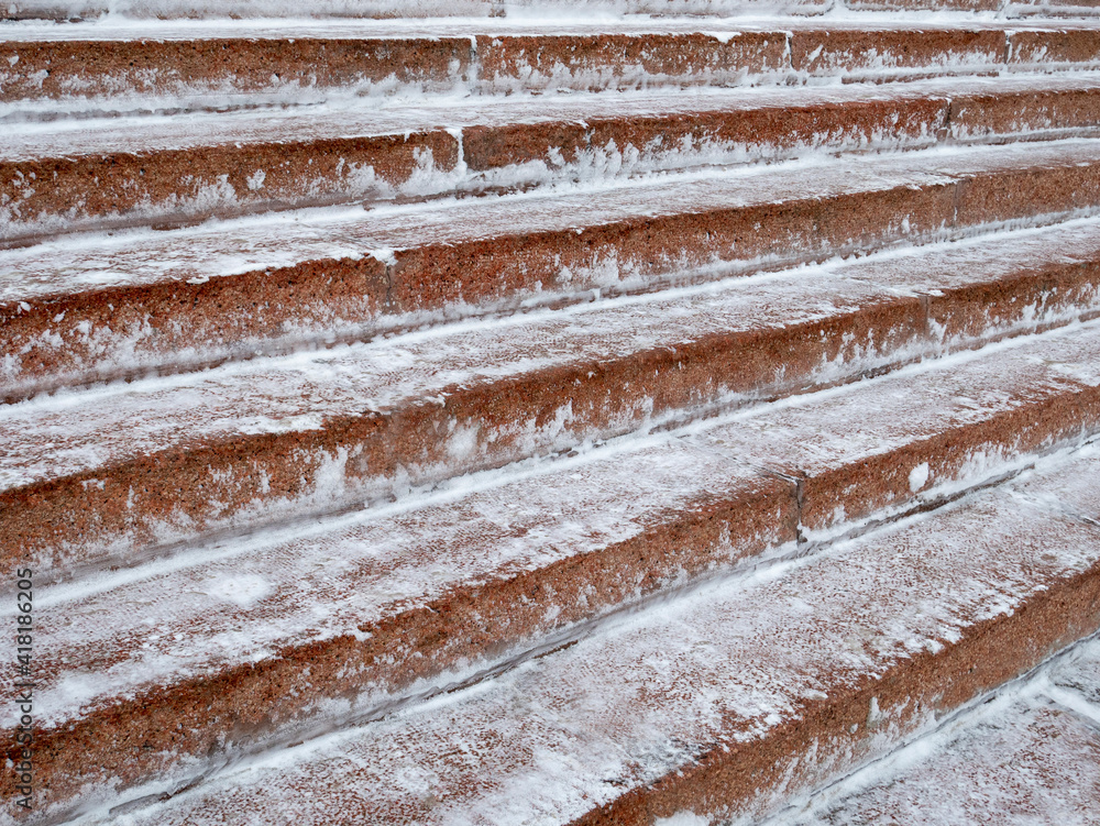 Red granite steps cleared of snow, in perspective.