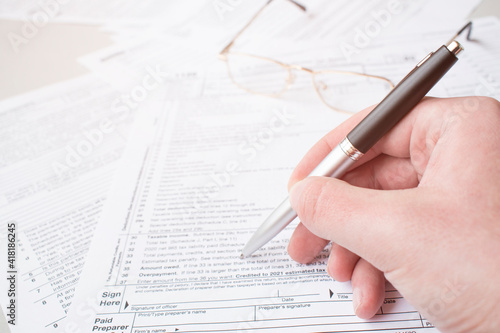 Close up of male accountant filling tax form. Man writing something sitting at his office. Filling individual income tax return form 1040, making financial report, home finances or economy concept