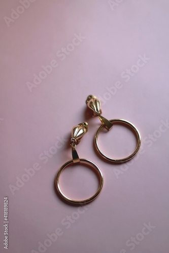 Vintage golden earrings on pink background. Selective focus.