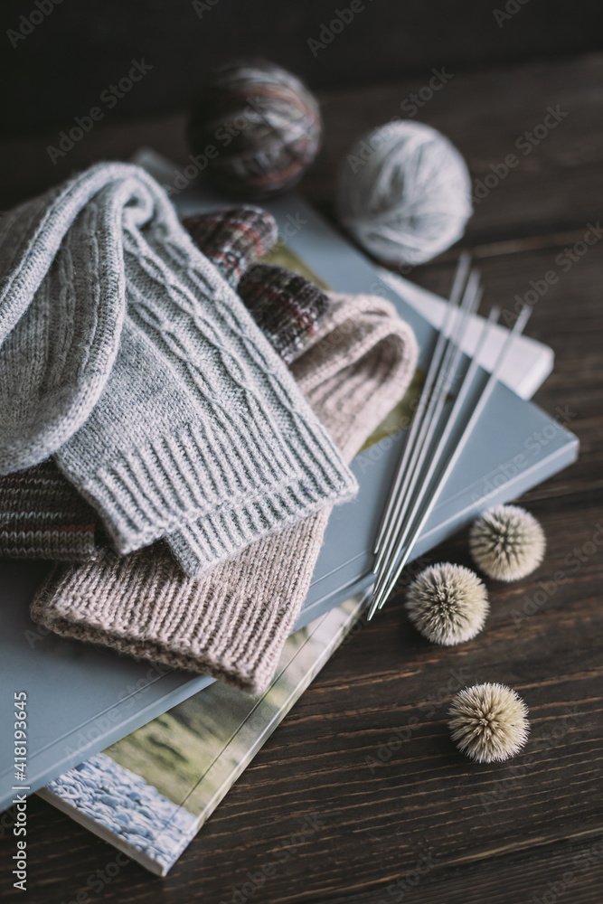 Fototapeta premium Hand knitting socks with needles and yarn balls ion a dark wooden background. Concept for handmade and hygge slow life.