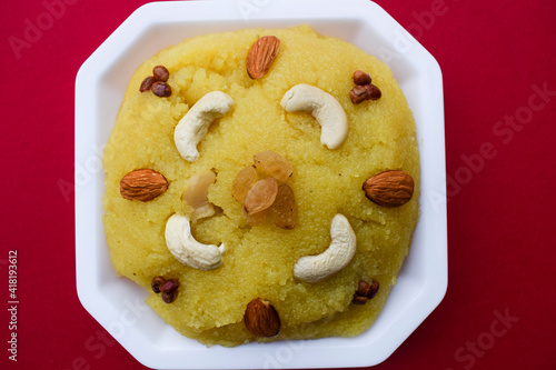 Traditional Indian dessert sweets made of semolina or rawa known as Kesari bath decorated with nuts garnished. south asian sweet on red background. blank space to write fonts text for greetings photo