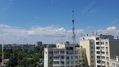 White clouds in blue sky over city high-rise buildings and communication tower antenna in residential district of European city