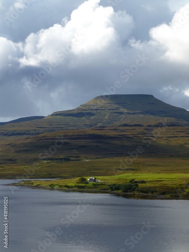 View across Loch Dunvegan to Healabhal Mhor (Macleod's Table), Isle of Skye with house on shores of the loch and rain clouds forming above the mountain