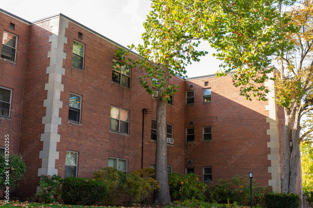 Shady side of a generic old apartment building, brick apartment building with concrete quoins, horizontal aspect Shady side of a generic old apartment building, brick apartment building with concrete quoins, horizontal aspect
