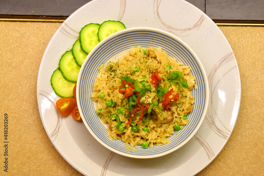 Chicken fried rice with mushroom, green pea. Seasoning with red chilli and side dish with organic fresh cucumber and tomato. Chicken fried rice with mushroom, green pea. Seasoning with red chilli and side dish with organic fresh cucumber and tomato.