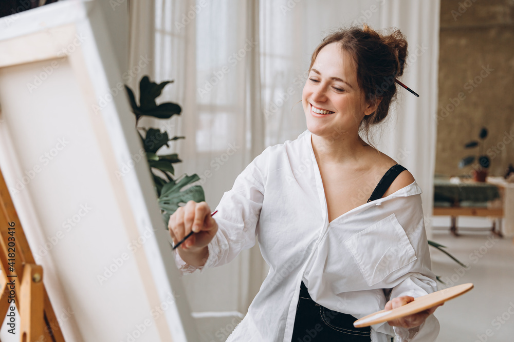 Artist painting on easel with brush and color palette Artist painting on easel with brush and color palette