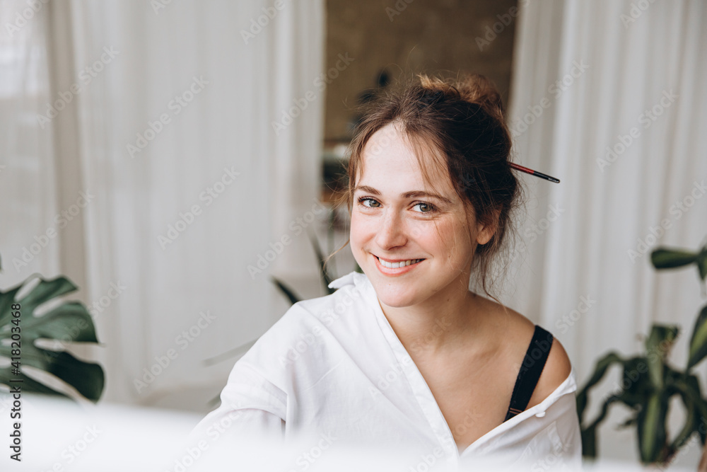 Artist sitting in front of canvas and painting with brush