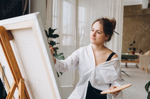 Inspired female artist drawing on canvas indoors