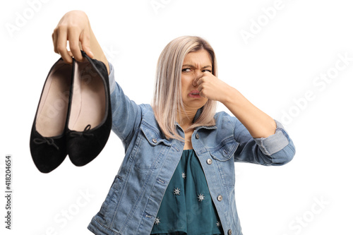 Foto Young woman holding a pair of smelly shoes