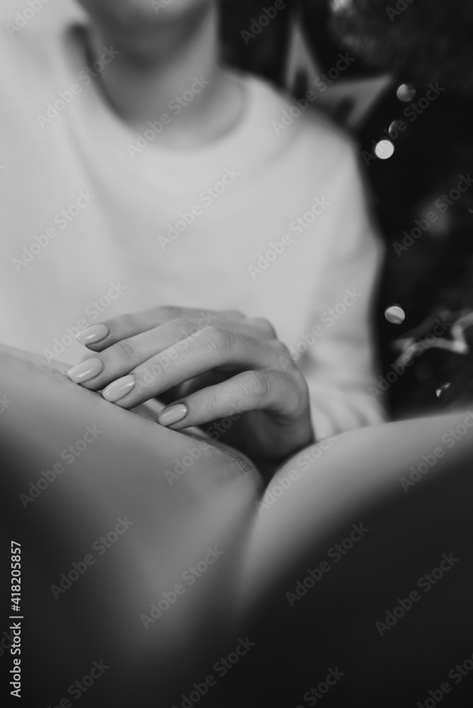 Woman in white reading interesting paper book while sitting near Christmas tree with bokeh at home. Black and white. Cozy winter pic of lady relaxing alone with novel. High quality photo