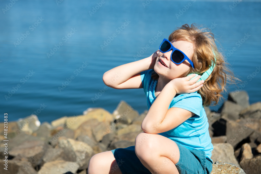 Kids music concept. Summer boy in headphones. Child in earphones outdoor. Carefree children.