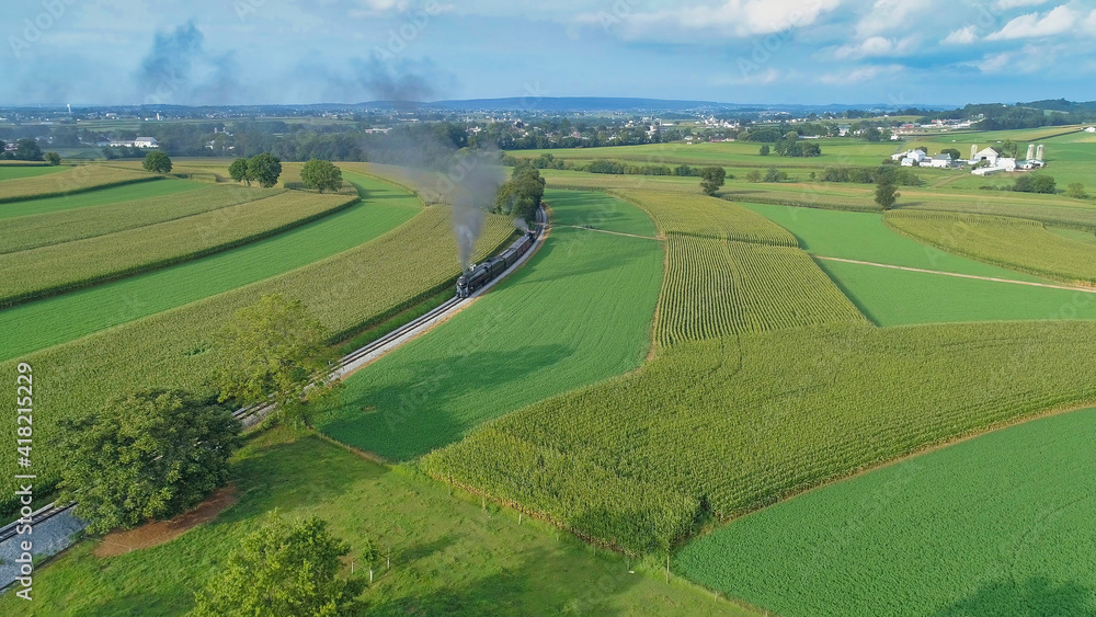 Aerial View of An Antique Restored Steam Locomotive Blowing Smoke and Steam Traveling Thru Farmlands and Countryside on a Sunny Summer Day