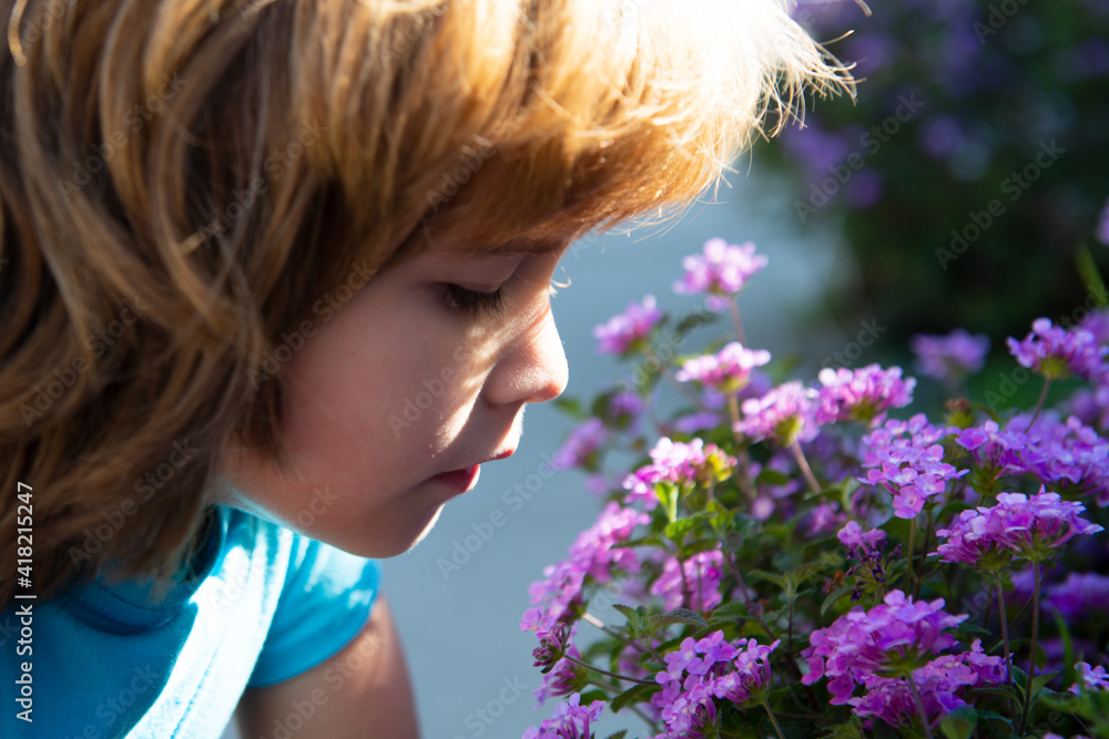 Spring or summer kid sniffs blooming branch. Cute child boy in blossom bloom garden. Spring or summer kid sniffs blooming branch. Cute child boy in blossom bloom garden.