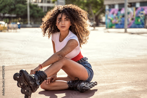 Foto Young fit black woman on roller skates relaxing after riding outdoors on urban street