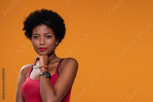 Attractive beautiful afro woman posing on orange studio background, photo