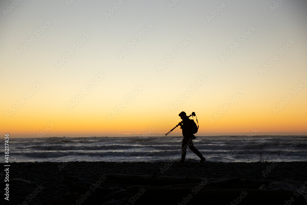 A photographer walking along the beach during sunset in Washington State